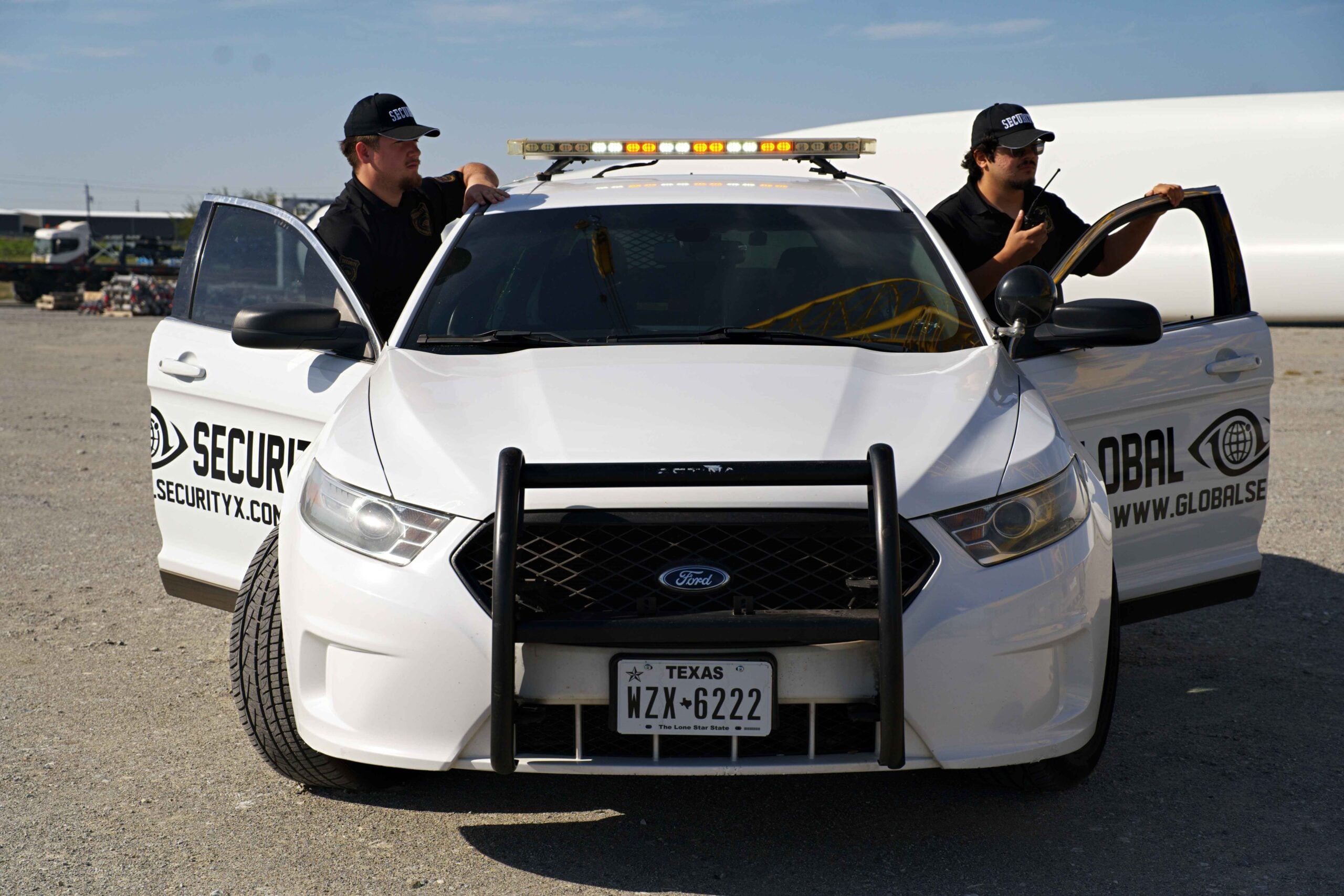 Security guards in front of a marked patrol car, emphasizing armed and unarmed guard services for petrochemical facility security in Louisiana.