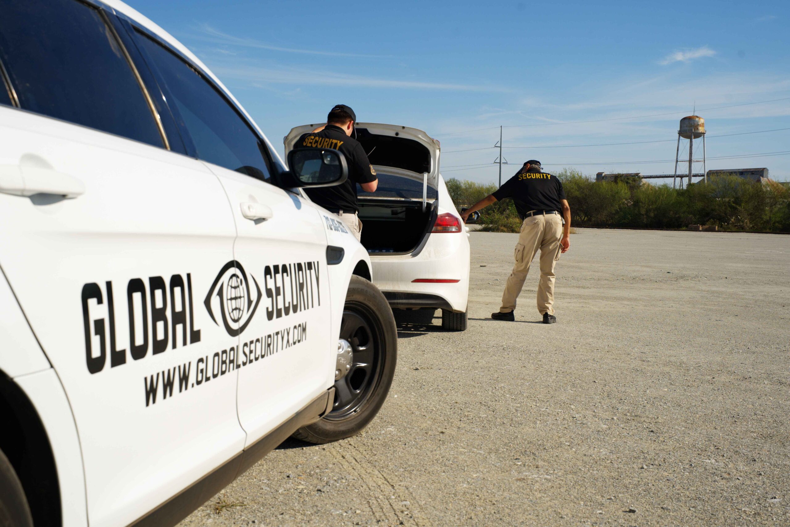 Global Security personnel inspecting a white vehicle, with a marked security car in the foreground, emphasizing professional security services in Louisiana.