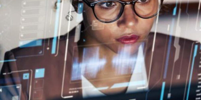 ### Key Elements

**Main Subject**  
- A young woman with glasses, focused on a computer screen.

**Objects**  
- A digital interface overlay with various data visualizations and graphs.

**Notable Features**  
- The woman appears engaged and thoughtful, with reflections of the digital interface on her face.

**Text/Symbols**  
- Data metrics and visual graphs displayed on the screen, indicating analytical work or data analysis.

### Overall Mood/Theme  
The image conveys a sense of concentration and modernity, highlighting themes of technology and data analysis. The woman's focused expression suggests a deep engagement with her work, emphasizing a professional and innovative environment.