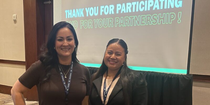 Alva Salinas and Samantha Duque pose at the 2026 Protos Security Conference in front of a presentation screen thanking attendees for their partnership.
