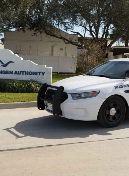 White security vehicle parked near a sign reading "Harlingen Authority," emphasizing construction site security services in Louisiana.