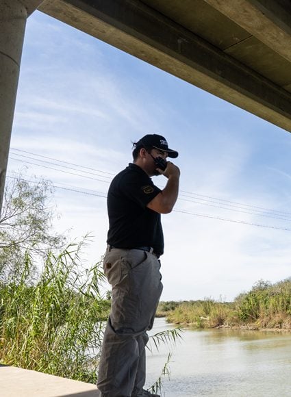 Unarmed security guard observing from under a bridge, emphasizing vigilance and professional presence in Houston's natural environment.